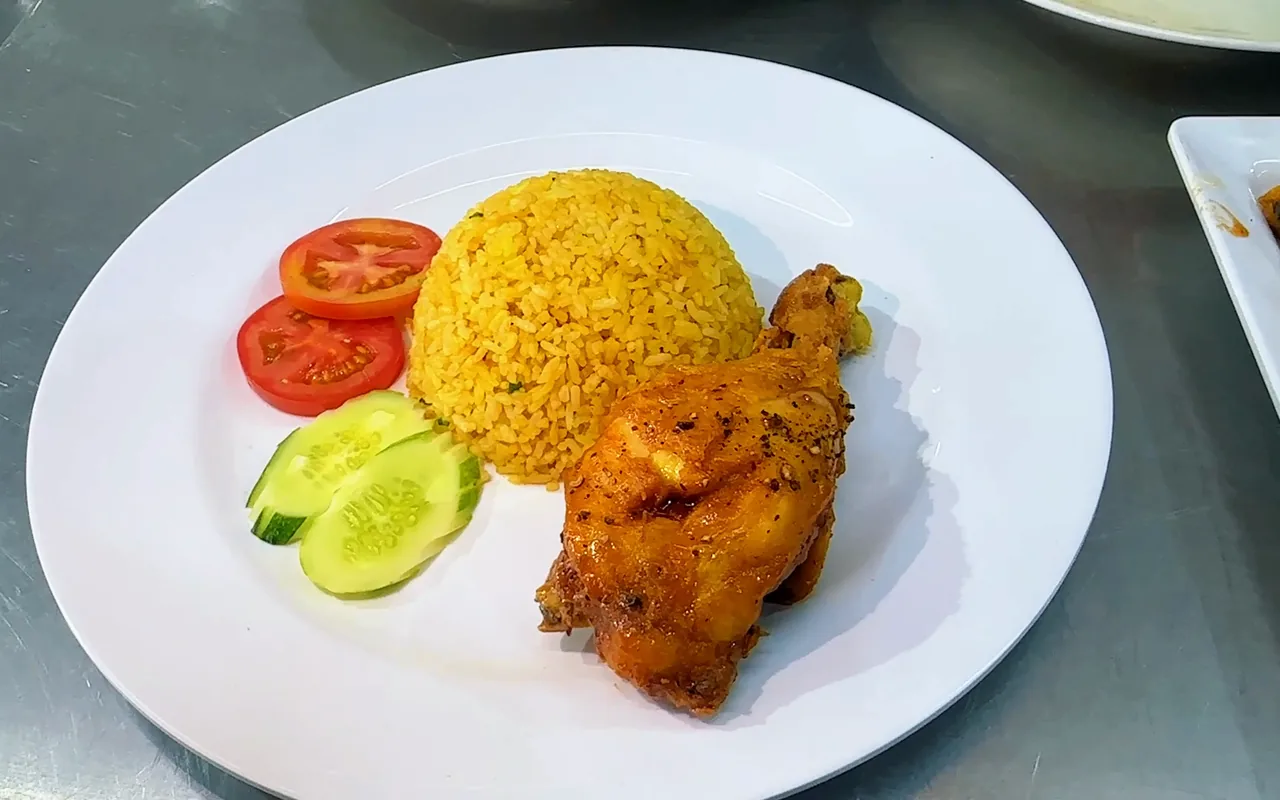Đĩa cơm gà xối mỡ: đùi gà da vàng giòn, cơm chiên vàng, cà chua và dưa leo — khung hình từ video khoá Cơm Gà Xối Mỡ, Bếp Cô Linh