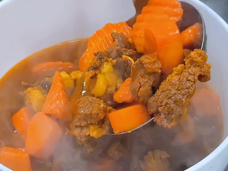 Vá múc thịt bò kho và cà rốt cắt gợn sóng, nước kho sánh đỏ — khung hình từ video khoá Bò Kho