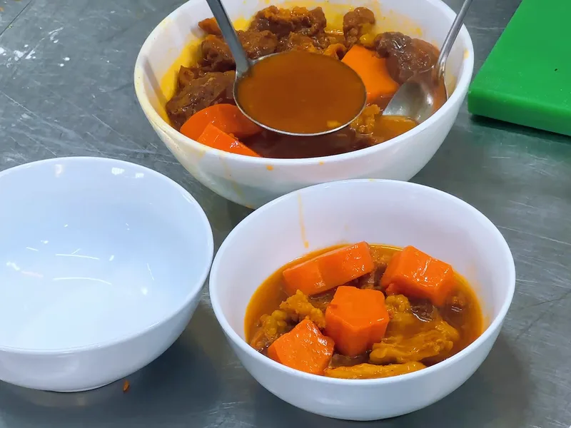 Múc nước bò kho vào chén để lên tô — khung hình từ video khoá Bò Kho