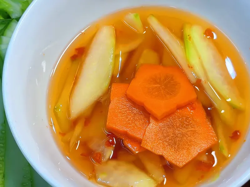 Chén nước mắm chấm bún chả với đu đủ xanh và cà rốt tỉa hoa — khung hình từ video khoá Bún Chả Hà Nội