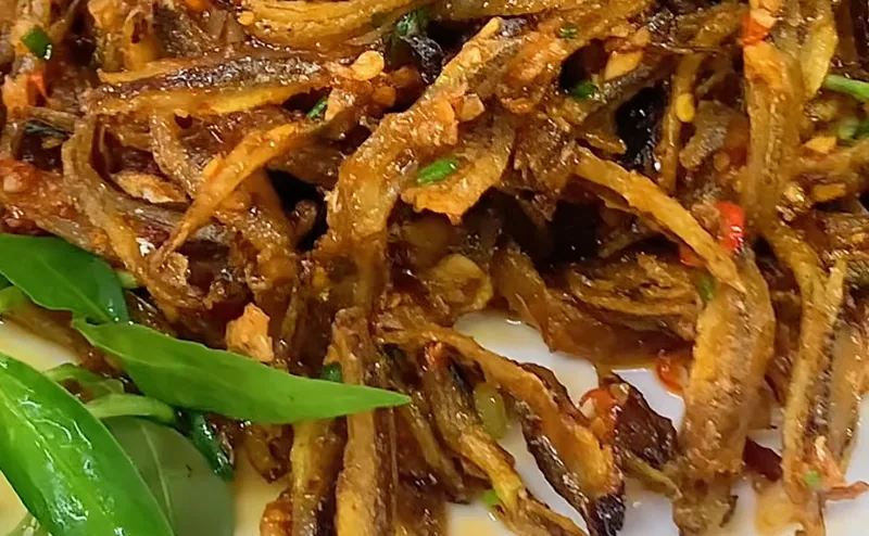 Dĩa cá cơm khô chiên vàng giòn sốt mắm tỏi, rắc hành lá và ớt, bày cùng rau thơm, món thật của Bếp Cô Linh