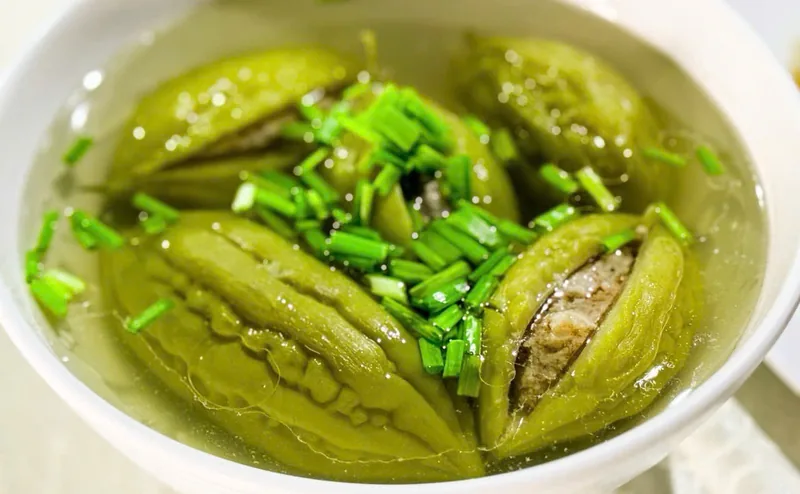 Tô canh khổ qua nhồi thịt nước trong, vỏ xanh bóng, nhân thịt lộ ra ở đường xẻ, rắc hành lá cắt nhỏ, món thật của Bếp Cô Linh