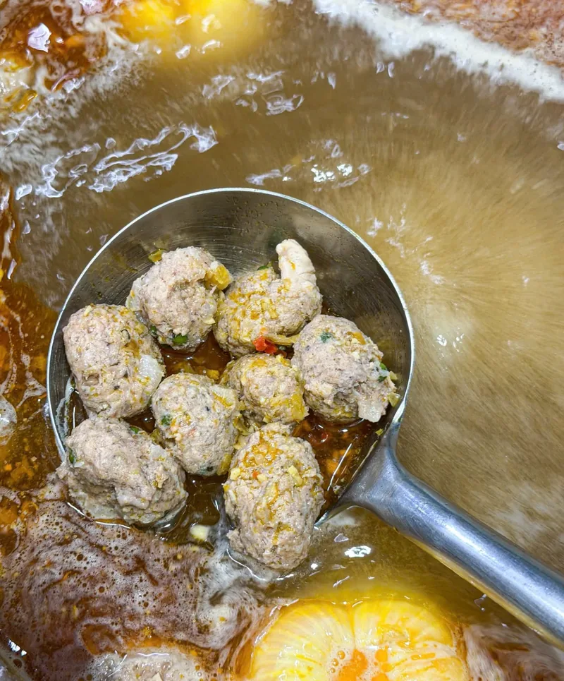 Muỗng chả sụn bò vừa múc lên từ nồi nước lèo bún bò Huế đang sôi
