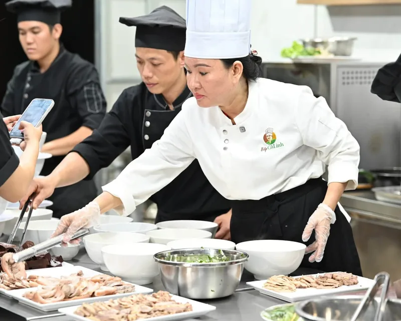 Cô Linh đang chia thịt luộc và huyết vào các tô bún bò Huế trong lớp học trực tiếp tại Bếp Cô Linh