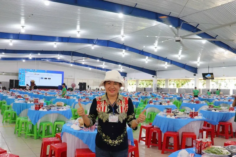 Cô Linh giơ ngón tay cái trong sảnh tiệc công ty, hàng trăm bàn đã bày sẵn món trước giờ khách vào
