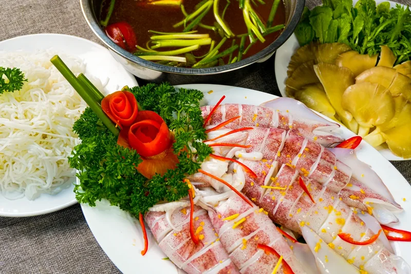 Đĩa mực nang xếp hoa cà chua, rau mùi tây, kèm bún, nấm và nồi nước lẩu của Bếp Cô Linh