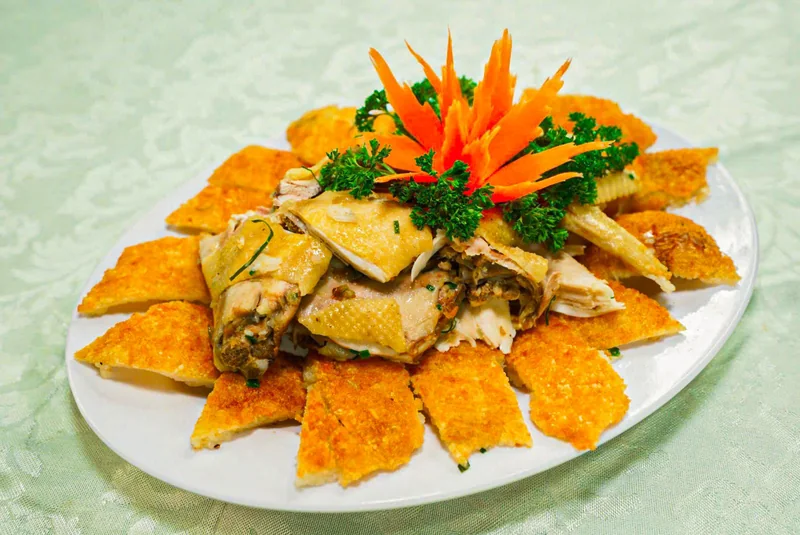 Đĩa gà bó xôi của Bếp Cô Linh: gà chặt miếng bày giữa, xung quanh là lớp xôi chiên vàng giòn, trang trí hoa cà rốt và rau mùi