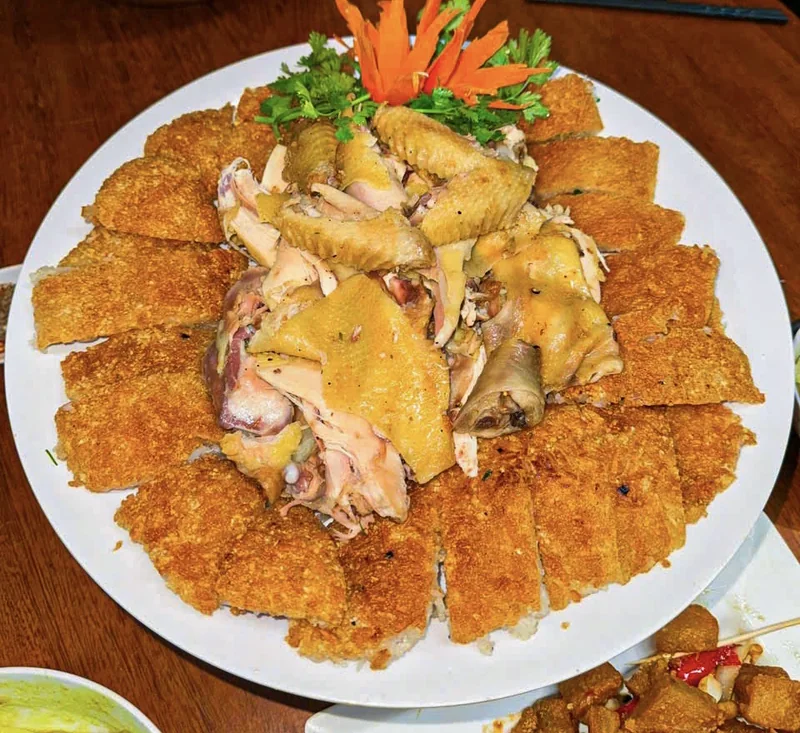 Gà bó xôi bày trên đĩa tròn lớn, gà chặt miếng ở giữa, xung quanh là những miếng xôi vàng giòn