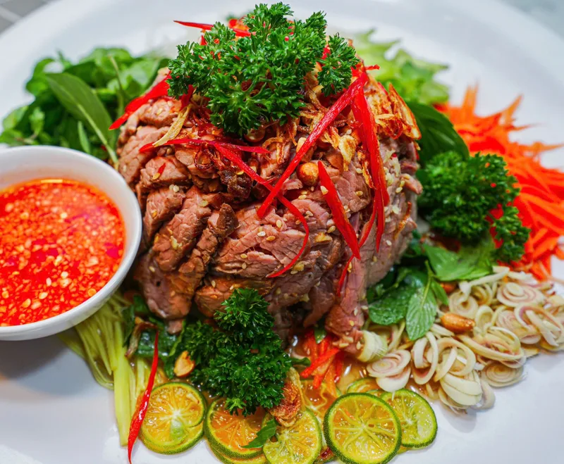 Gỏi bò nướng của Bếp Cô Linh: thịt bò nướng xếp cao, rau thơm, xoài, cà rốt và chén nước chấm