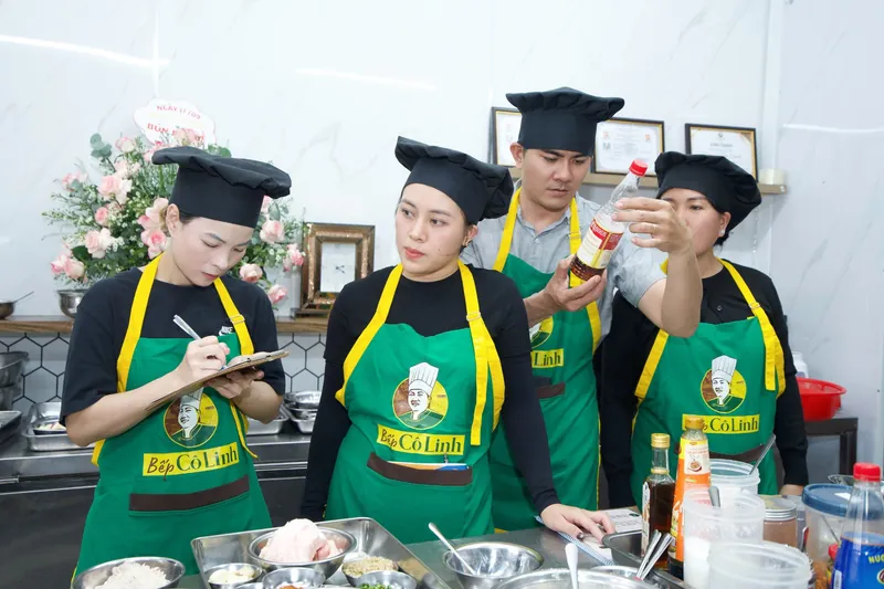 Học viên ghi chép và kiểm tra chai gia vị trước khi nấu trong lớp học bún bò Huế trực tiếp