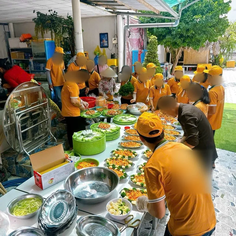 Đội của một học viên ở Vĩnh Long đang sơ chế và bày món cho tiệc nhiều bàn, trên bàn dài bày sẵn hàng chục đĩa món
