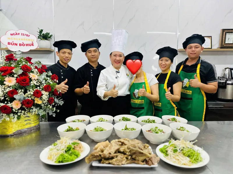 Cô Linh và đội ngũ Bếp Cô Linh chụp ảnh mừng ngày khai giảng khoá Bún Bò Huế, phía trước là dãy tô bún bò Huế thành phẩm