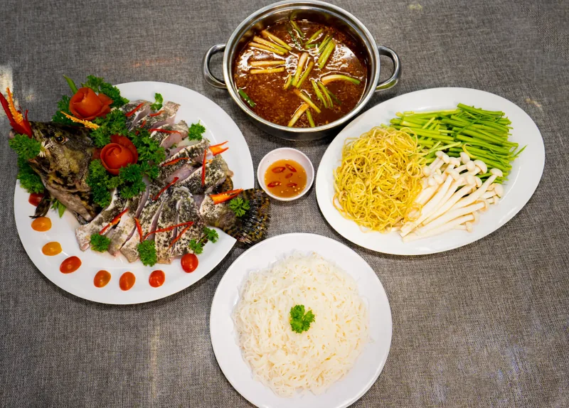 Lẩu cá bống mú: đĩa cá thái lát, nồi nước lẩu, bún, rau và nấm bày sẵn