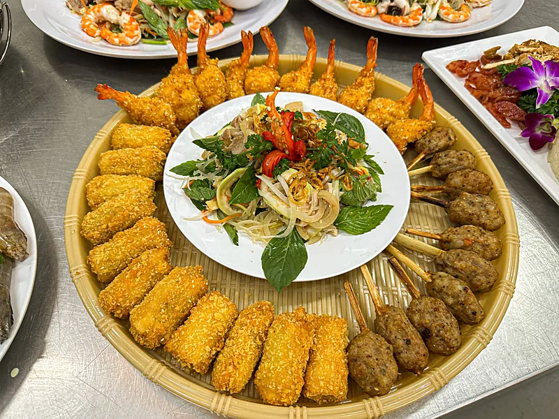 Mâm món khai vị gồm tôm chiên xù, chả giò chiên, nem nướng sả và đĩa gỏi đặt ở giữa
