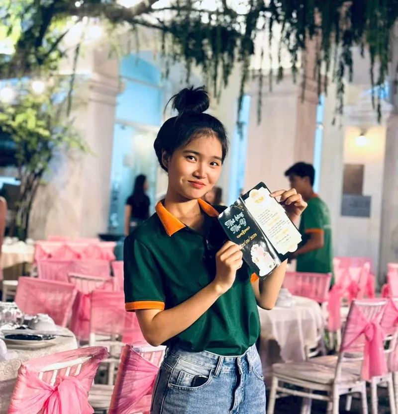 Hoàng Nhi, con gái cô Linh, cầm thực đơn giữa những bộ bàn ghế phủ nơ hồng tại tiệc ở khu An Khánh