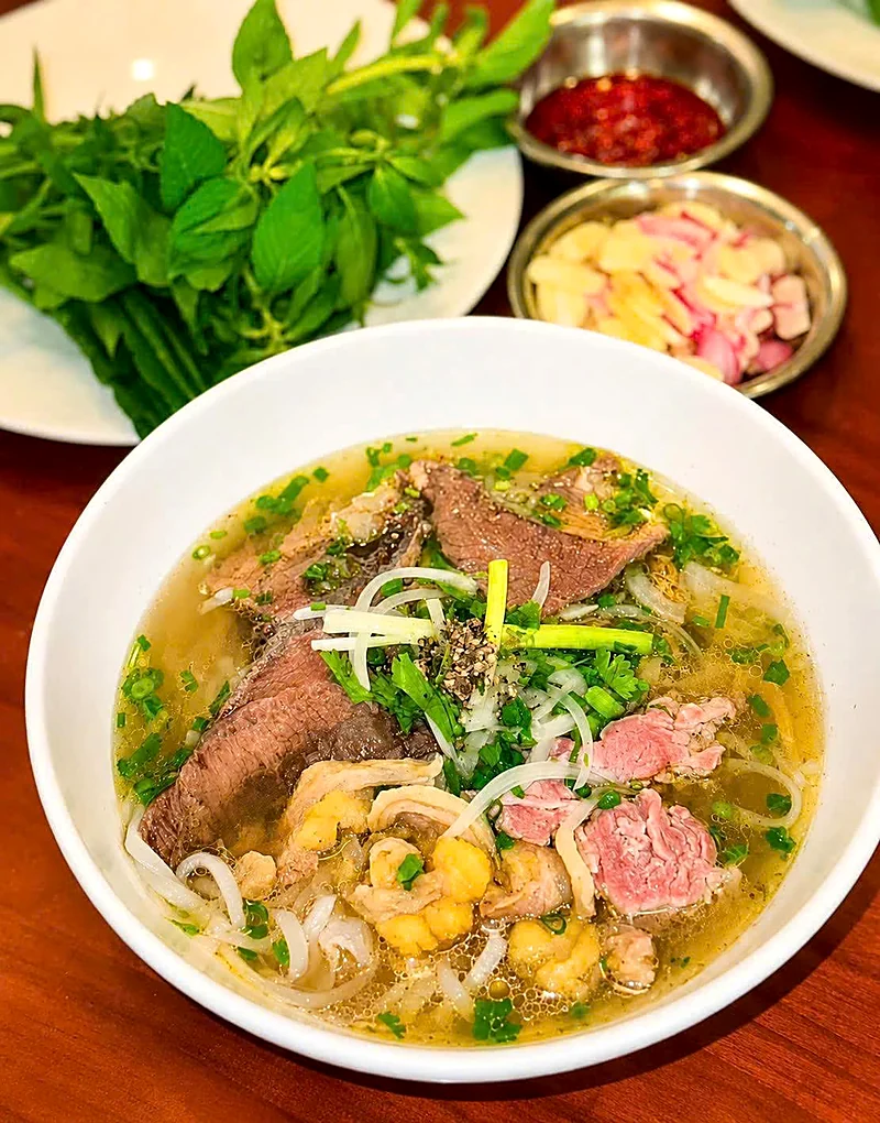 Tô phở bò tái, nạm, gầu nước dùng trong, ăn kèm rau quế, sa tế và hành ngâm — thành phẩm khoá Phở Bò