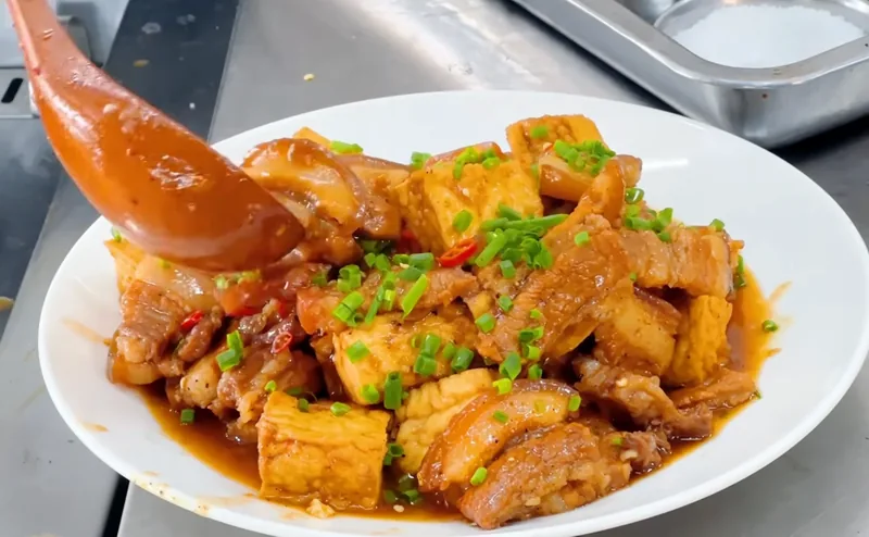 Đĩa thịt kho đậu hũ màu nâu đậm đà, rắc hành hoa và ớt, món thật của Bếp Cô Linh