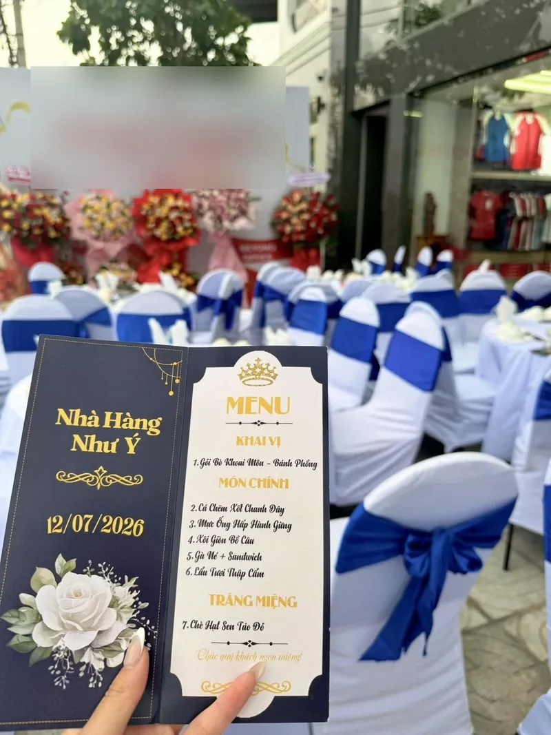 Tờ thực đơn của Nhà Hàng Như Ý gồm một món khai vị, năm món chính và chè hạt sen táo đỏ tráng miệng, đặt giữa dãy bàn ghế phủ nơ xanh