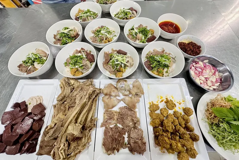 Các tô bún bò Huế xếp sẵn cùng đĩa huyết, thịt luộc, giò, chả, chén sa tế và hành tỏi ngâm