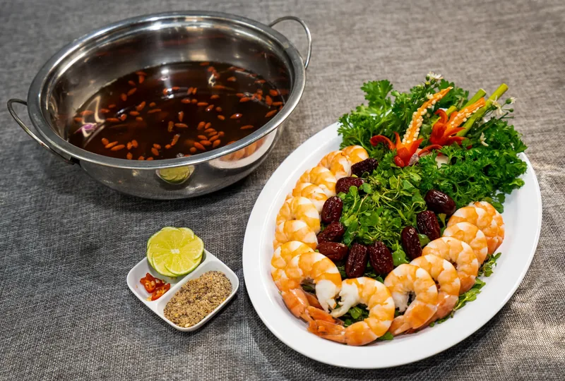 Tôm tiềm ngũ quả: tôm luộc xếp quanh rau, táo đỏ, kèm nồi nước tiềm có kỷ tử và chén muối ớt chanh