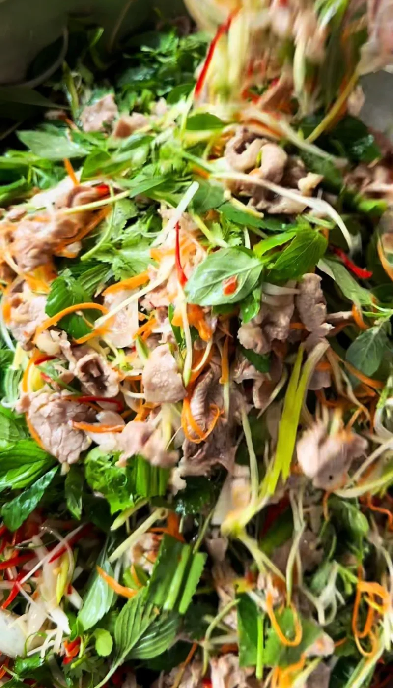 Đang trộn gỏi bò với rau thơm, cà rốt và hành tây ngay tại tiệc